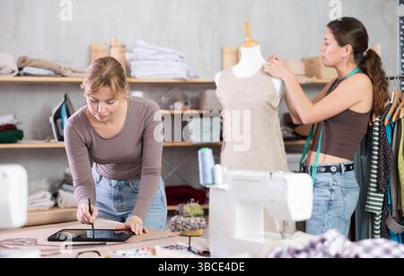Le stilisti femminili creano abiti di design in officina Foto Stock