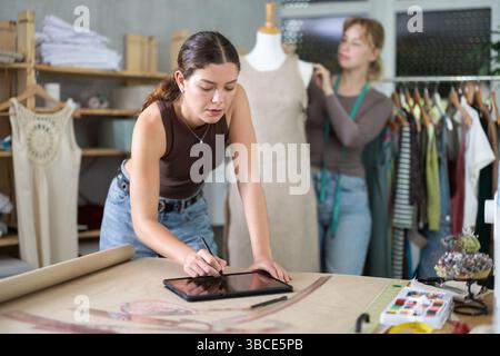 Le stilisti femminili creano abiti di design in officina Foto Stock