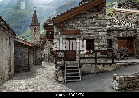Una vista pittoresca di un tradizionale villaggio alpino in pietra con una vecchia chiesa tra le vecchie case in pietra a Bonneval sur Arc, Francia. Foto Stock