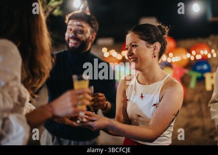 Amici che festeggiano una festa di compleanno gioiosa in un cortile decorato in modo festoso Foto Stock