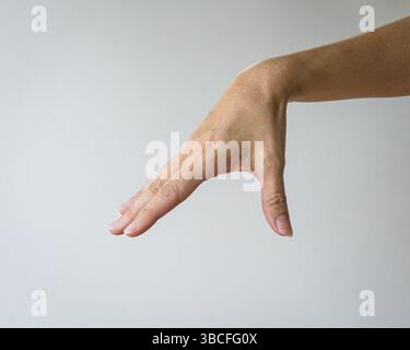 La mano donna forma un gesto di scendere per scegliere qualcosa. Isolato su sfondo bianco. Foto Stock