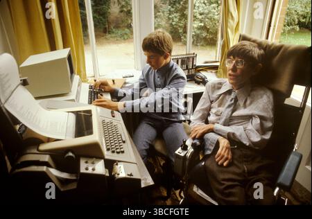 Il professor Stephen Hawking a casa con il figlio maggiore Robert. Seduto nel suo ufficio domestico con computer e una macchina per l'elaborazione di testi. Il suo ufficio faceva parte del soggiorno. Cambridge, Cambridgeshire, Inghilterra 1981,1980s UK HOMER SYKES Foto Stock