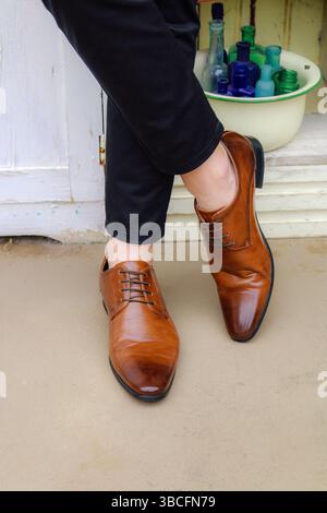 Uomo in piedi gambe incrociate con scarpe abbronzate e senza calze Foto Stock