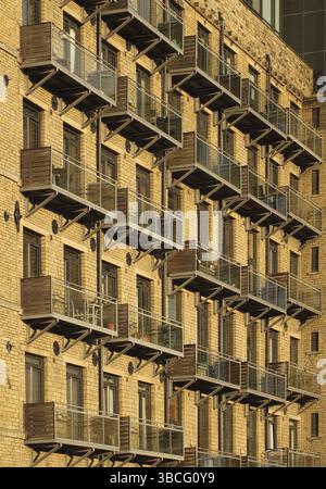 Vista prospettica della facciata di un grande edificio vecchio mulino in pietra convertito in appartamenti con moderni balconi in vetro Foto Stock