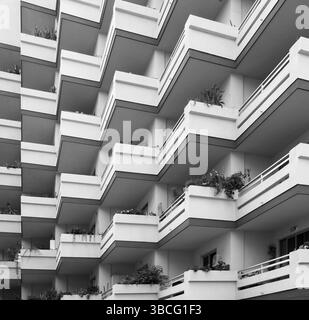 Immagine monocromatica di balconi ripetuti su un grande e moderno edificio di appartamenti in cemento con piante Foto Stock