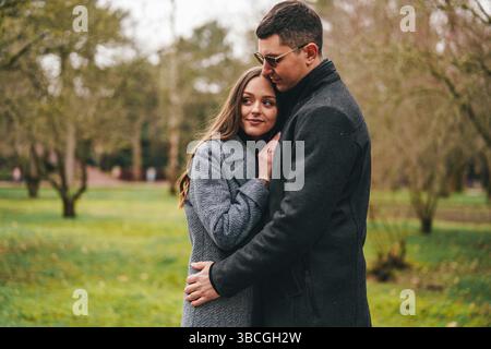La coppia gode di momenti intimi insieme in un parco tranquillo durante un pomeriggio fresco Foto Stock