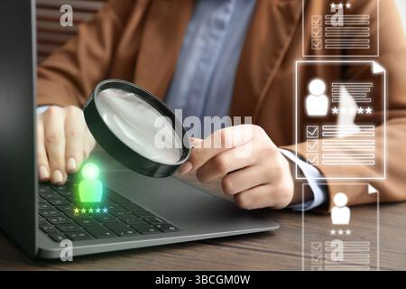 Reclutamento, ricerca dipendenti. Responsabile delle risorse umane con lente d'ingrandimento tramite laptop, primo piano. Riprende sullo schermo virtuale Foto Stock