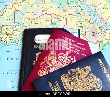Tre passaporti del Regno Unito con due passaporti UE pre-Europen scaduti e un passaporto biometrico del Regno Unito in corso su una pagina atlas aperta in Africa Foto Stock