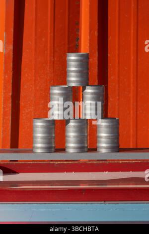 Sei lattine d'argento impilate in una piramide su sfondo arancione e rosso. New York, Stati Uniti Foto Stock