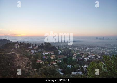 Alba su un vasto paesaggio urbano con lontani grattacieli e colline nebbiose. Los Angeles, Stati Uniti Foto Stock