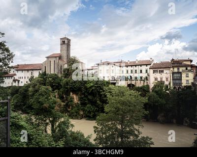 Vista panoramica di Cividale del Friuli con la sua torre della chiesa e gli edifici colorati arroccati sopra il fiume Natisone, circondato da vegetazione lussureggiante e Foto Stock