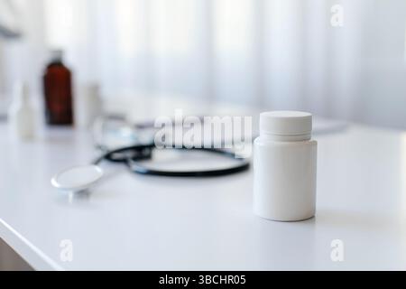Posto di lavoro medico con bottiglia di plastica bianca su scrivania bianca, Foto Stock