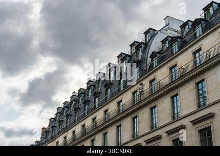 Facciata dell'edificio parigino con finestre dormitori che mostrano il cielo nuvoloso sullo sfondo Foto Stock