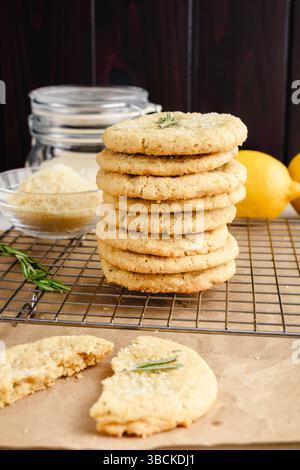 Biscotti con zucchero al rosmarino e limone impilati su un rack metallico: Vista laterale di biscotti con zucchero appena sfornati su un rack di raffreddamento in filo metallico Foto Stock