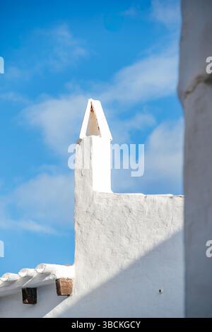 Vista ravvicinata di un camino immacolato di bianco, caratteristico della tradizionale architettura mediterranea. Le linee pulite e la consistenza bianca incarnano il loro aspetto Foto Stock