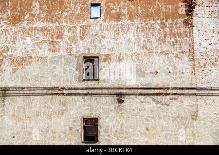 Parte del muro rosso di una vecchia casa in rovina con tre finestre rettangolari. Dalla serie di finestre del mondo. Foto Stock