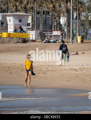 Donna anziana che cammina lungo il litorale della spiaggia di Barceloneta, Barcellona, Spagna Foto Stock