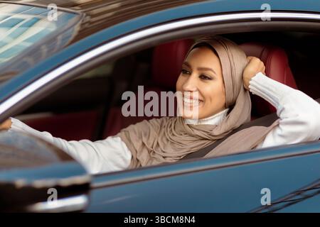 Allegra donna musulmana che guida la sua nuova auto Foto Stock