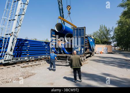 Caricamento del tubo in ghisa nel camion per il trasporto con carroponte. Foto Stock