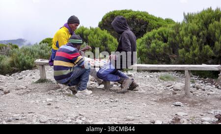 Tanzania: 7. Gennaio 2016: Giovani apprendisti facchini al campo abse sul monte Kilimanjaro fanno una pausa per godersi una partita a dama Foto Stock