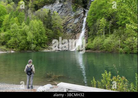Escursionista femmina guardando la cascata Saarbach e turchesi laghetto balneabile nelle Alpi Svizzere vicino Vilters su un bel pomeriggio di primavera Foto Stock