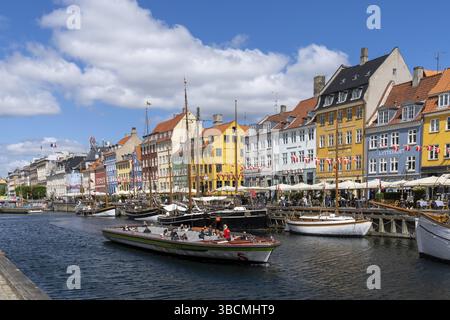 Copenhagen, Danimarca - 13 Giugno 2021: Vista dello storico quartiere di Nyhavn nel centro di Copenhagen con una chiatta turistica per la crociera in primo piano Foto Stock