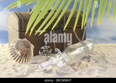 Messaggio in una bottiglia con vecchie monete, vecchio petto e conchiglia nella sabbia Foto Stock