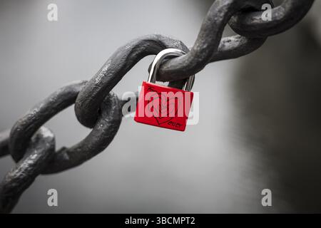 Lucchetto rosso appeso su una grande catena con cuore e parole per sempre Foto Stock