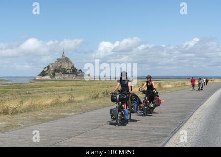 Francia - 18 agosto 2019: Turisti in bicicletta a lunga distanza che visitano e viaggiano verso il famoso Mont Saint-Michel nel nord della Francia Foto Stock