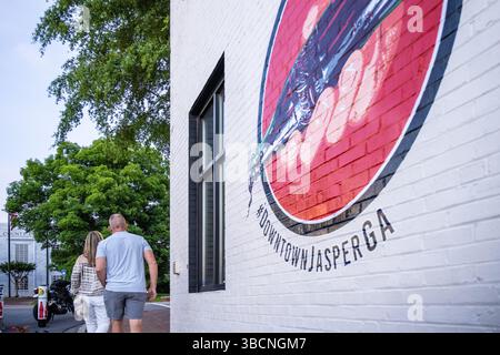Una coppia passeggia davanti a un murale della Coca-Cola al crepuscolo nel centro di Jasper, Georgia. (USA) Foto Stock