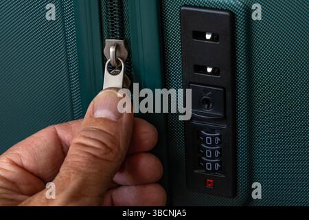Un viaggiatore controlla la cerniera della sua valigia durante il check-in in aeroporto, un ladro cerca di aprire la borsa Foto Stock