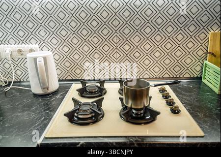 Primo piano di una stufa a gas integrata all'interno di una cucina, con una pentola piccola Foto Stock