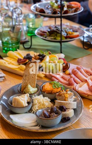 Piatto di antipasti con prosciutto, formaggio e vari tipi di spalmabili, per creare una deliziosa esperienza culinaria per un pasto al coperto Foto Stock