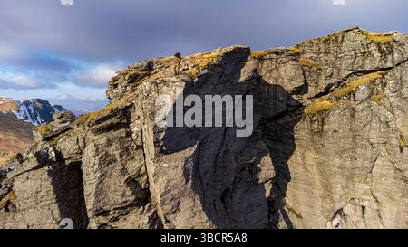 Un fotografo solitario si erge in cima al Cobbler (Ben Arthur) nelle Alpi Arrochar della Scozia, catturando le viste spettacolari da una delle vette più iconiche. Foto Stock