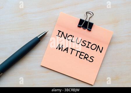 L'inclusione conta testo su blocco note rosa che rappresenta l'importanza della diversità e dell'appartenenza in tutti gli spazi Foto Stock