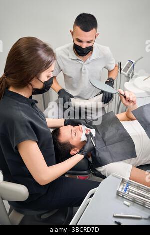 Lo Stomatologo mostra il dente problematico e spiega come trattarlo Foto Stock