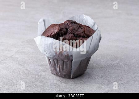 Muffin al cioccolato ricco in tazza di carta tulipano su superficie in pietra grigia con spazio per le copie. Foto Stock