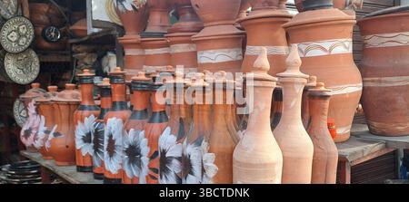 Vasi o brocche d'acqua in terracotta tradizionali marocchine in terracotta, vasi con motivi floreali si stagliano su un ripiano in legno, che mostra la maestria artigianale Foto Stock