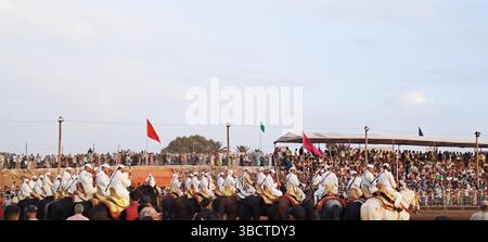 Uomini marocchini a cavallo durante una fantasia, una tradizionale mostra di equitazione in marocco, che si esibisce di fronte a una grande folla Foto Stock