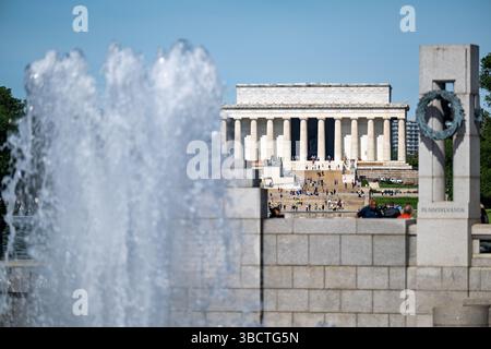 WASHINGTON DC - la fontana del World War II Memorial si erge in modo prominente sul National Mall, con l'iconico Lincoln Memorial visibile in lontananza. Completato nel 2004, il World War II Memorial onora i 16 milioni di americani che hanno prestato servizio nelle forze armate durante la guerra, tra cui più di 400.000 che hanno perso la vita. Il monumento presenta una piscina arcobaleno centrale circondata da 56 pilastri di granito che rappresentano gli stati e i territori degli Stati Uniti durante la guerra. Situato all'estremità orientale della piscina riflettente, il monumento crea un collegamento visivo tra il Lincoln Memorial e il Washington Monument Foto Stock