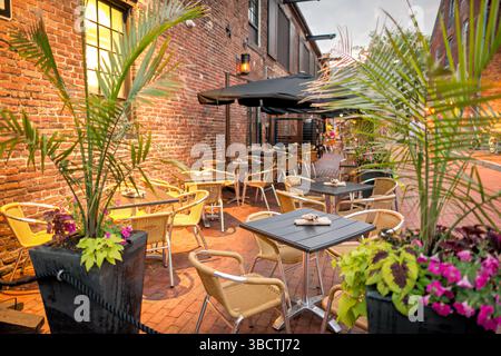 Virtue Feed and Grain Restaurant, posti a sedere all'aperto Alexandria Virginia // ALEXANDRIA, Virginia, Stati Uniti - posti a sedere all'aperto al Virtue Feed and Grain Restaurant offre opzioni ristorative all'aperto nel quartiere storico della città vecchia di Alexandria. Il ristorante occupa un magazzino ristrutturato del XIX secolo che un tempo serviva come negozio di alimenti e cereali al 106 di South Union Street. Situato ad appena un isolato dal lungomare del fiume Potomac, lo spazio all'aperto consente ai commensali di gustare i pasti mentre si sperimenta il fascino storico della città vecchia di Alexandria. I posti a sedere nel patio estendono la capacità del ristorante in t Foto Stock