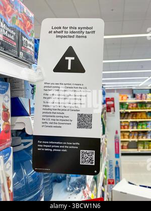 East Gwillimbury, Ontario, Canada - 20 maggio 2025: Un cartello su uno scaffale del negozio Shoppers Drug Mart che spiega il simbolo T per quanto riguarda la tariffa interessata Foto Stock