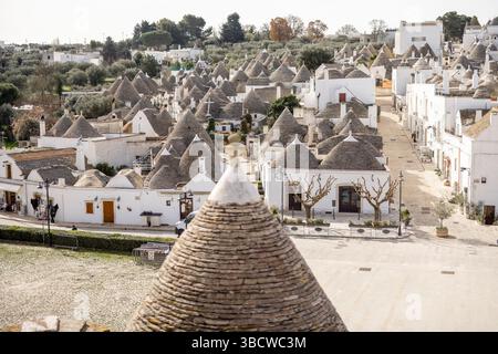 Una vista panoramica di Alberobello, in Italia, che mostra le iconiche case dei trulli con tetti conici in pietra sotto il luminoso sole del sud. Patrimonio dell'UNESCO e fascino senza tempo Foto Stock