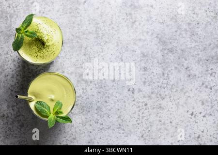 Due bicchieri di tè Dalgona matcha latte, frusta di bambù e polvere di matcha su sfondo grigio. Vista dall'alto. Spazio per il testo. Foto Stock