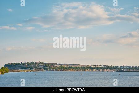 Vista distante sulla baia di Cardiff verso Penarth, Galles del Sud, in una tranquilla serata soleggiata con cielo blu e nuvole sparse sul lungomare della città. Foto Stock