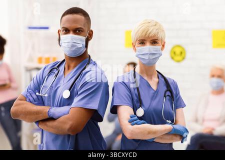 Due diversi medici in maschere mediche che posano in piedi in ospedale Foto Stock