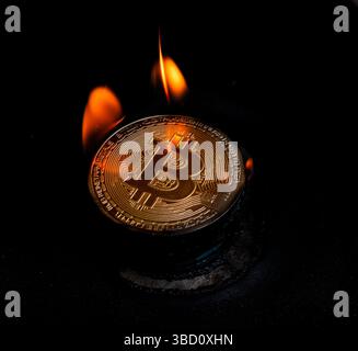 Simboli brucianti di Bitcoin in fiamme che rappresentano la crisi finanziaria e il collasso economico Foto Stock