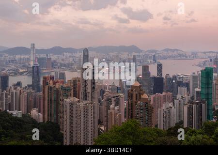 Vista serale durante un colorato tramonto sullo skyline dell'Isola di Hong Kong e di Kowloon con tutti i grattacieli che creano una giungla di cemento vista picco Foto Stock