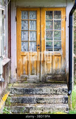 Porta gialla e scala di pietra su un vecchio cottage abbandonato Foto Stock