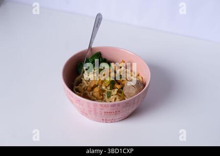Una ciotola di invitante zuppa di spaghetti di pollo con polpette e verdure verdi offre un pasto casalingo confortevole Foto Stock